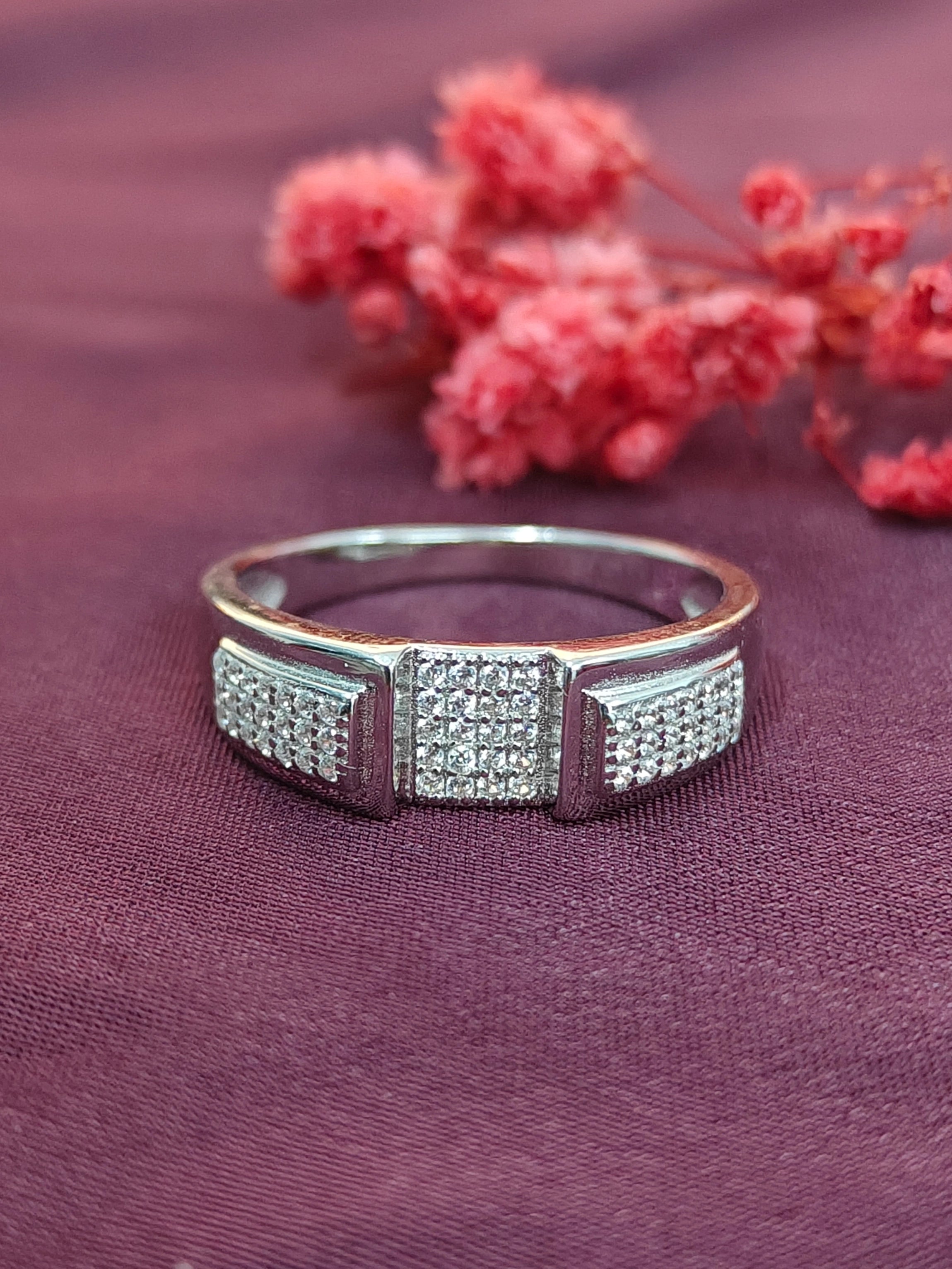 Silver ring with diamond accents on a purple fabric background